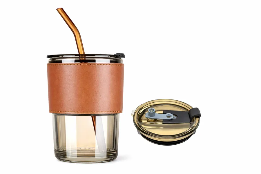 Glass cup with tan leather sleeve and metal straw
